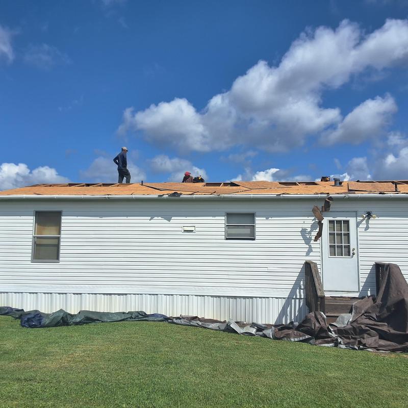 Roof decking installation on residential home under clear sky