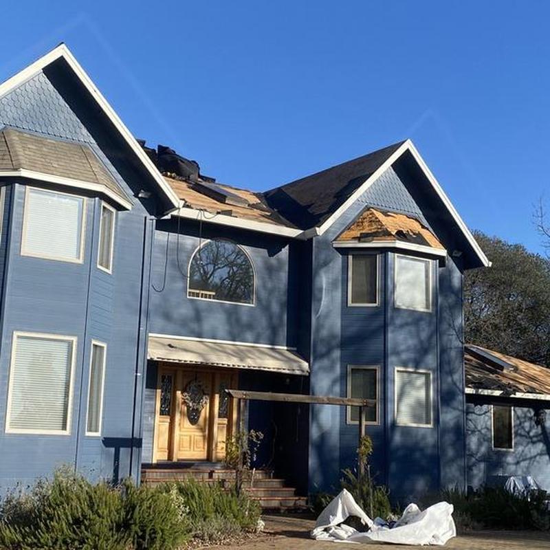 Asphalt roof with missing shingles on blue house
