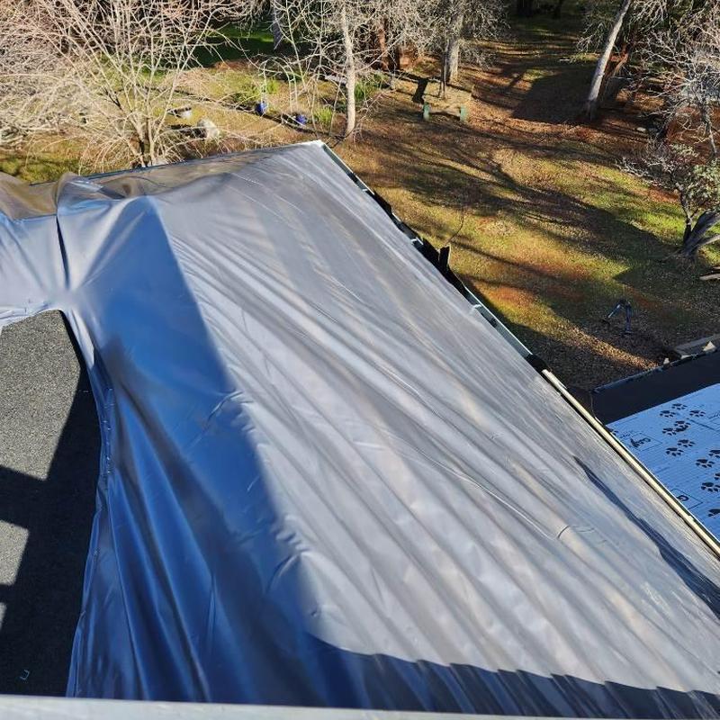 Asphalt roof under protective tarp on residential home