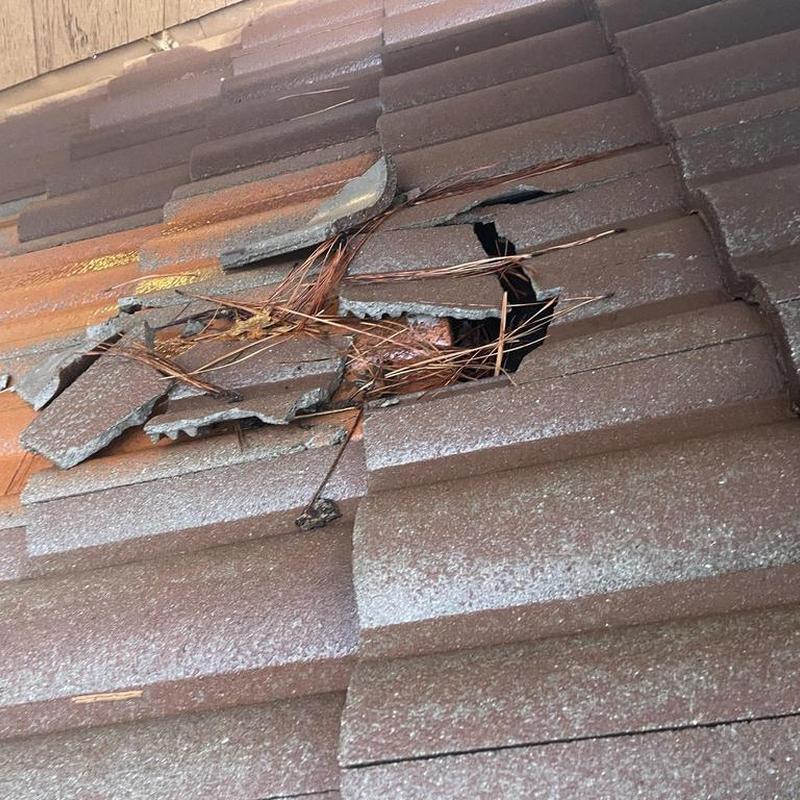 Tile roof with broken and missing tiles, debris present