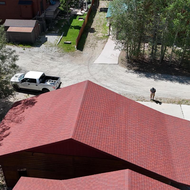 Asphalt shingle roof with red shingles above driveway