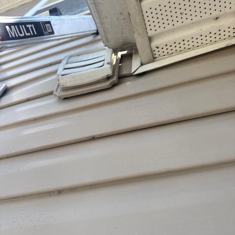 Vinyl siding near soffit vent with damage and gaps