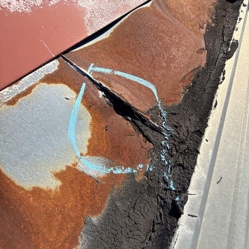 Rust-damaged metal roof panel with corrosion and cracks