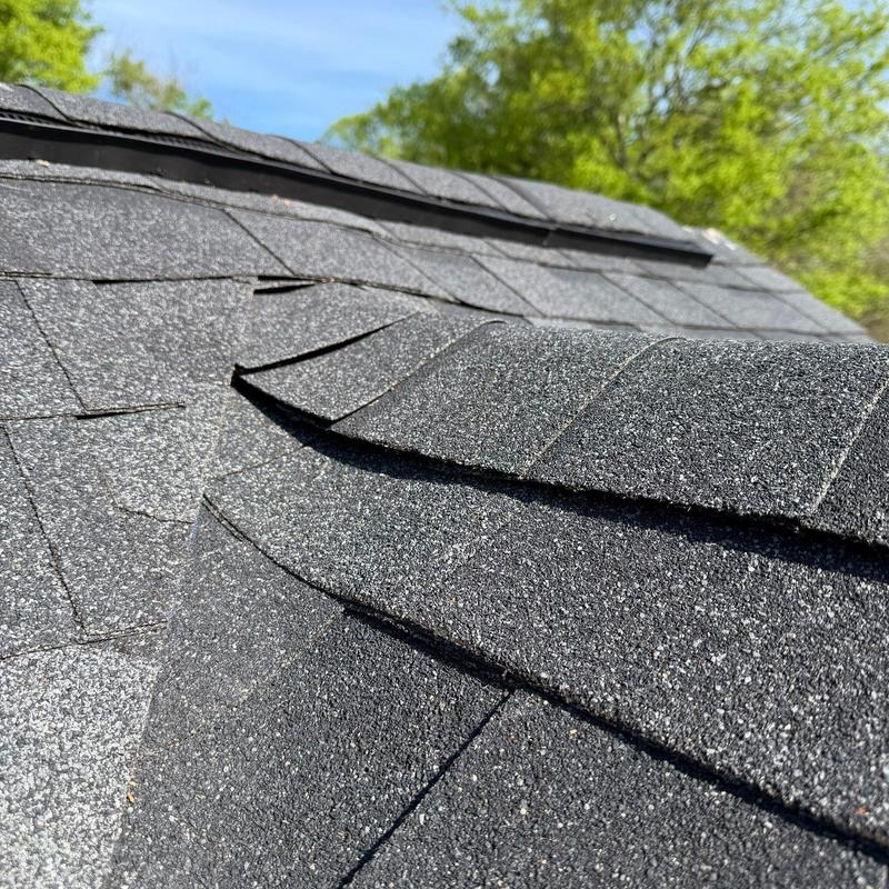 Asphalt shingle roof with visible damage and lifting