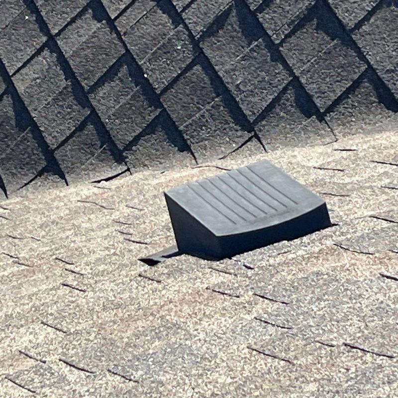 Roof shingles and vent with hail damage on residential roof