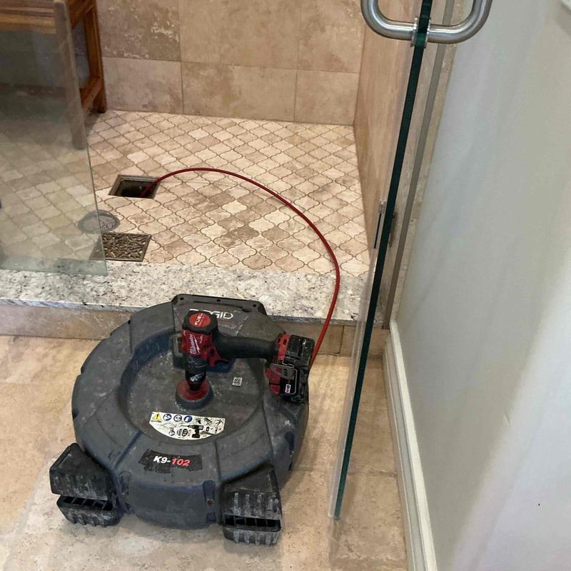 Shower drain with rigid snake tool clearing clog