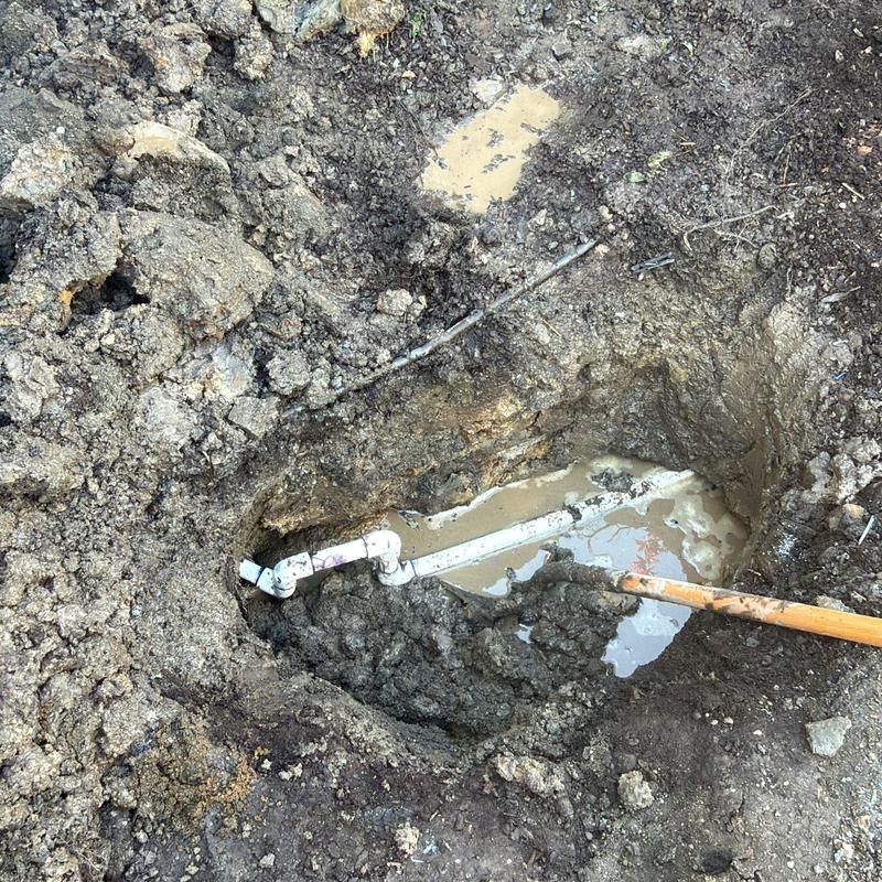 PVC water service pipe buried in muddy excavation site PVC water service pipe buried in muddy excavation site