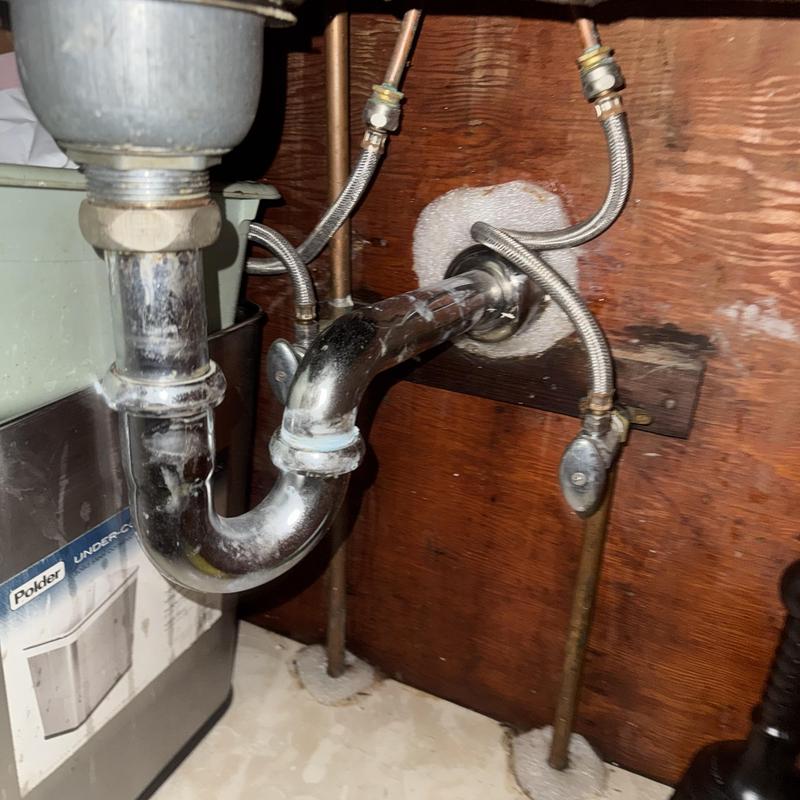Kitchen sink drain pipes with water supply lines under cabinet