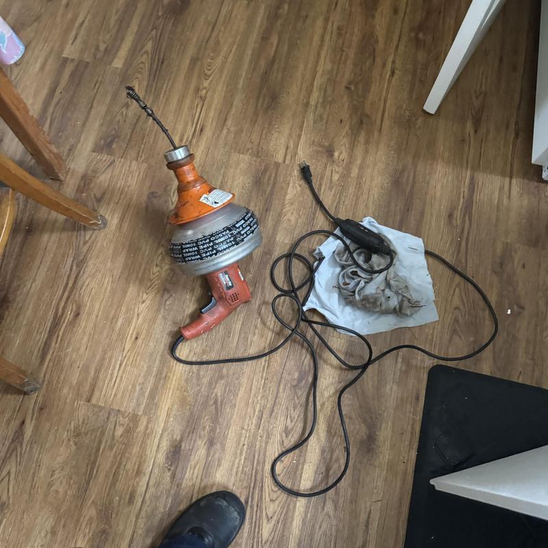 Kitchen sink drain snake machine on floor with cloth