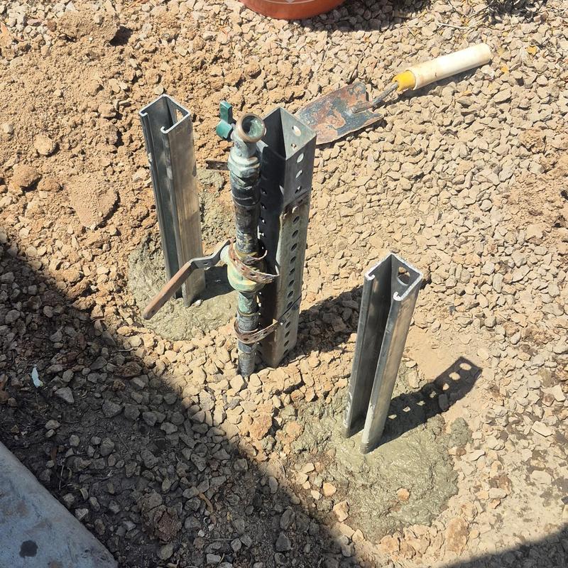 Hose bib installation with metal brace posts in gravel