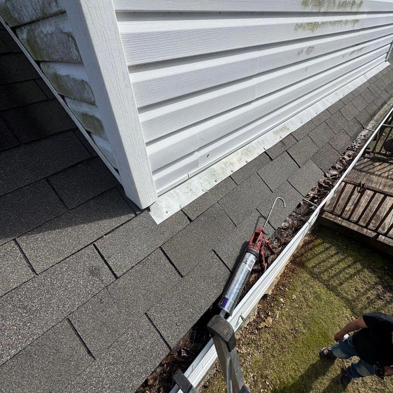 Roof shingles and flashing with caulking gun on ladder