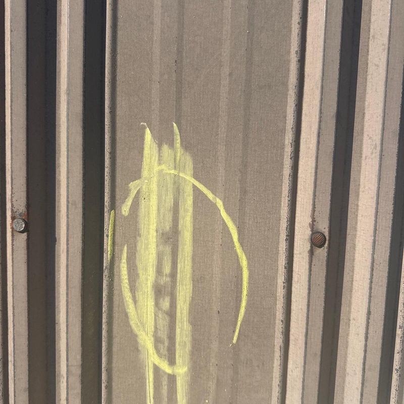 Metal roof panel hail damage marked for repairs