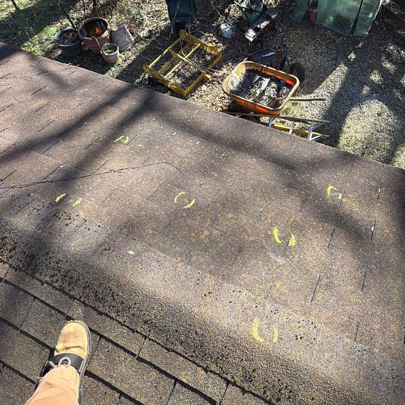 Roof shingles with yellow chalk marks highlighting damage