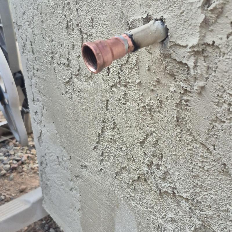 Copper outdoor hose bib pipe installation on stucco wall