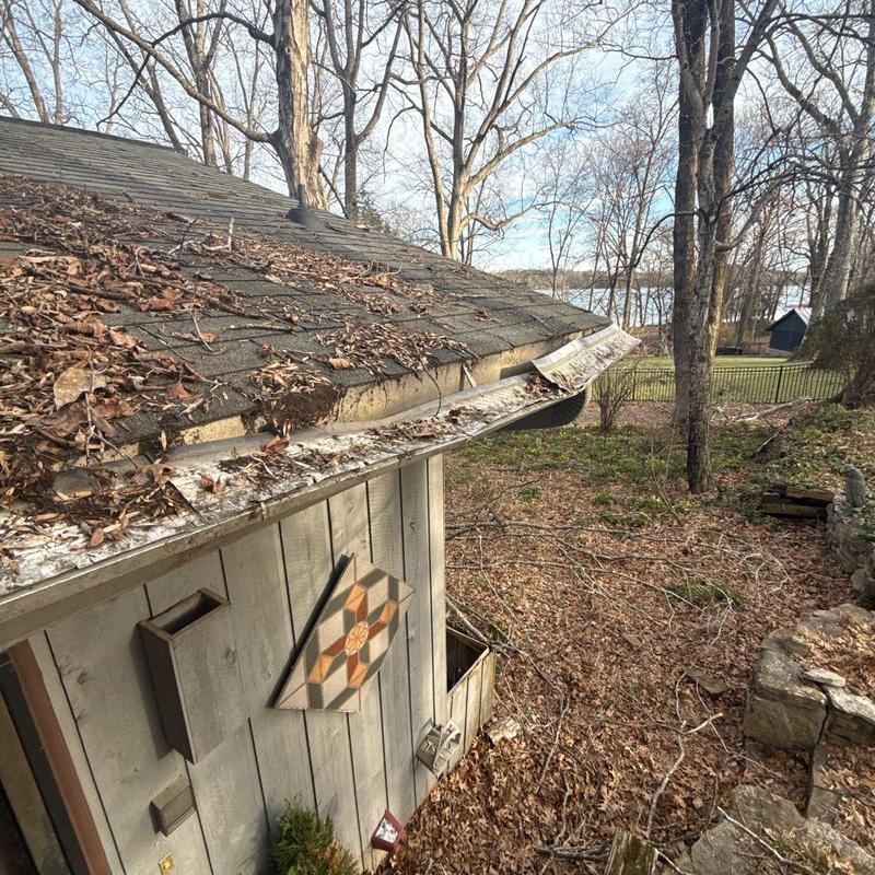 Damaged roof shingles and bent gutter with debris