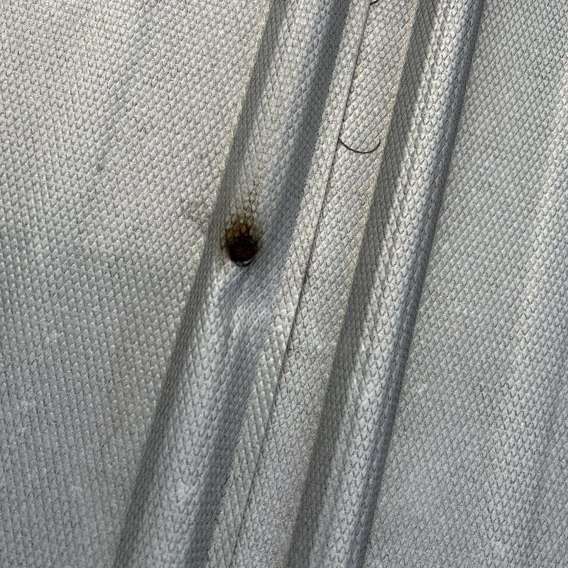 Roof tarp with rusted metal fastener and hole damage