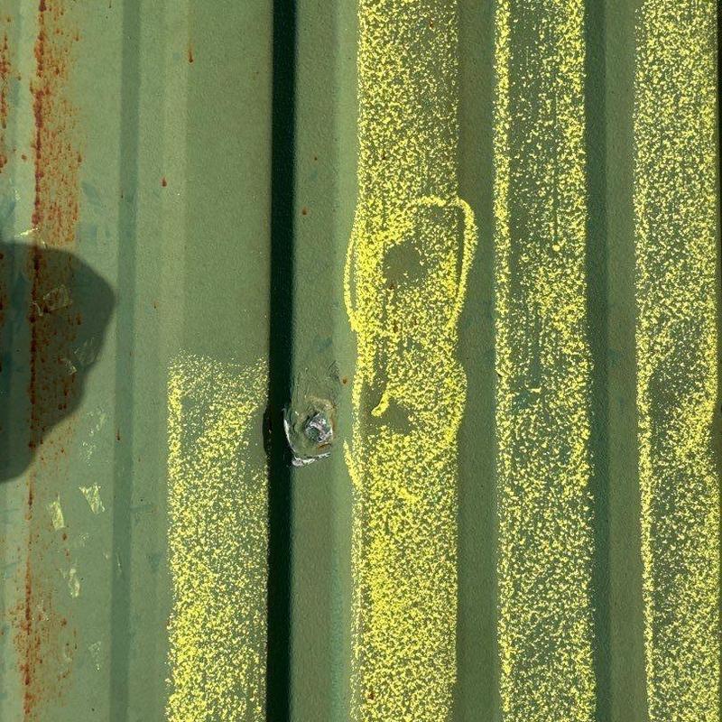 Metal roof panel with hail damage marked in yellow paint