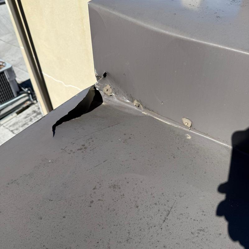 Roof flashing with torn metal and holes near wall joint