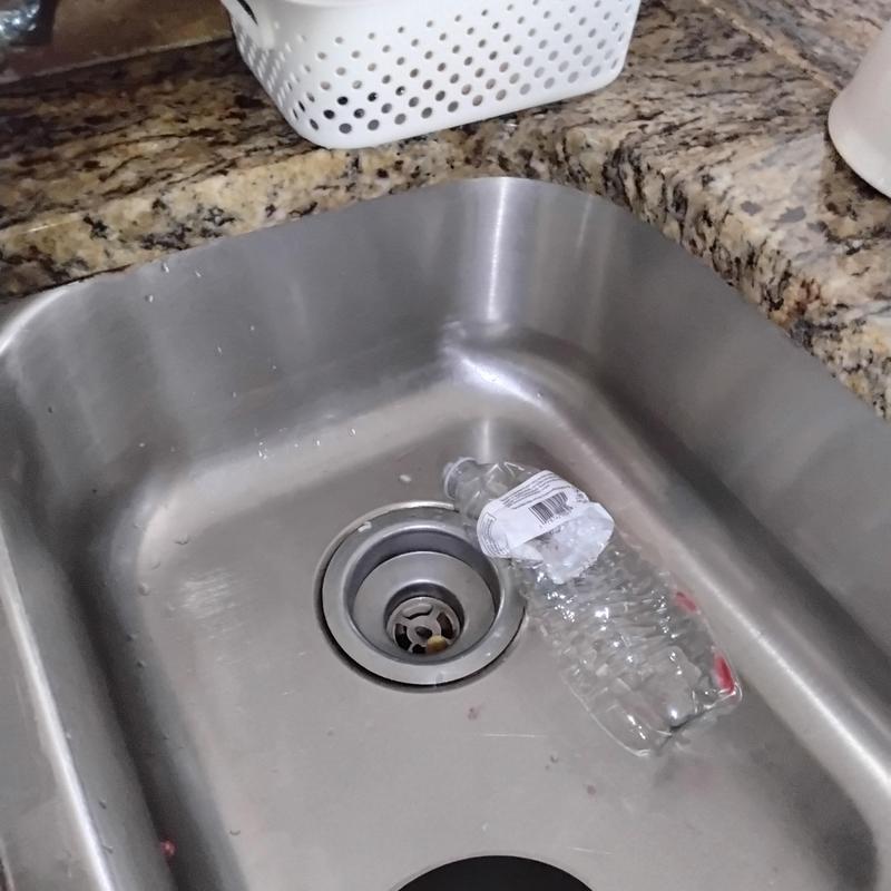 Basket strainer in stainless steel kitchen sink with water