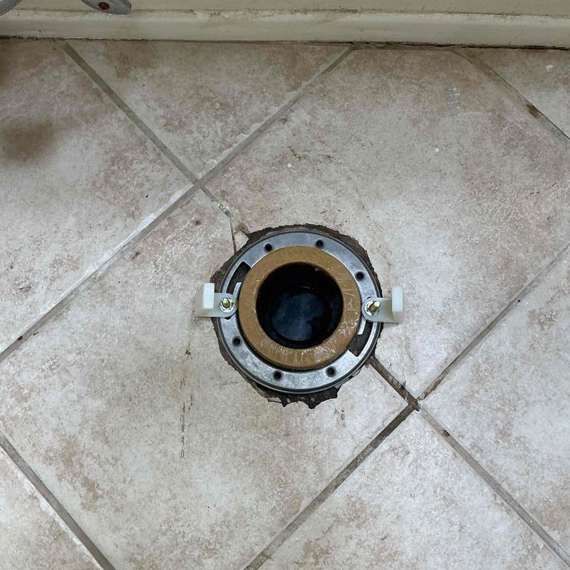Toilet flange with integrated ring bracket installed on tile floor