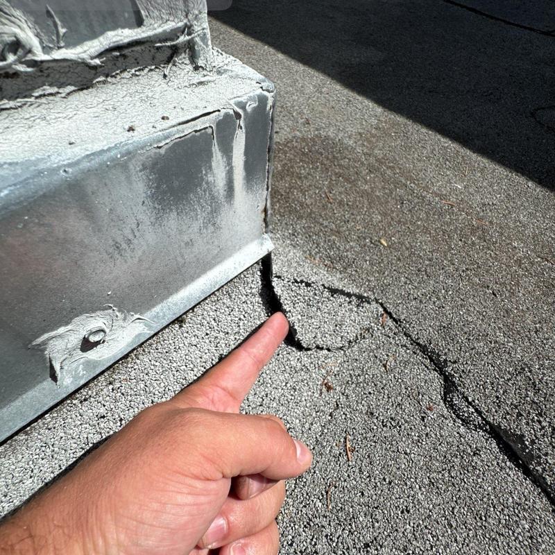 Roof gravel surface cracked near metal flashing edge Roof gravel surface cracked near metal flashing edge