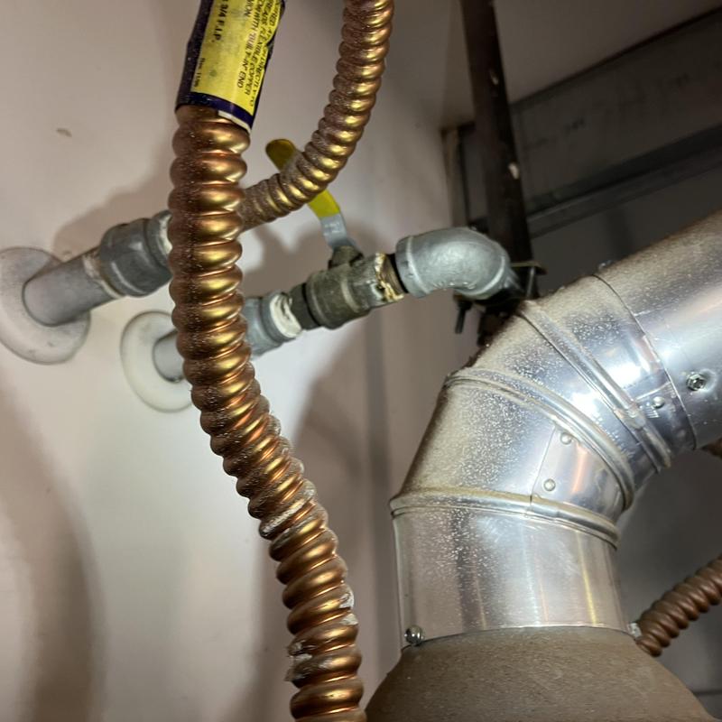 Gas water heater flexible gas line and vent pipe close-up Gas water heater flexible gas line and vent pipe close-up