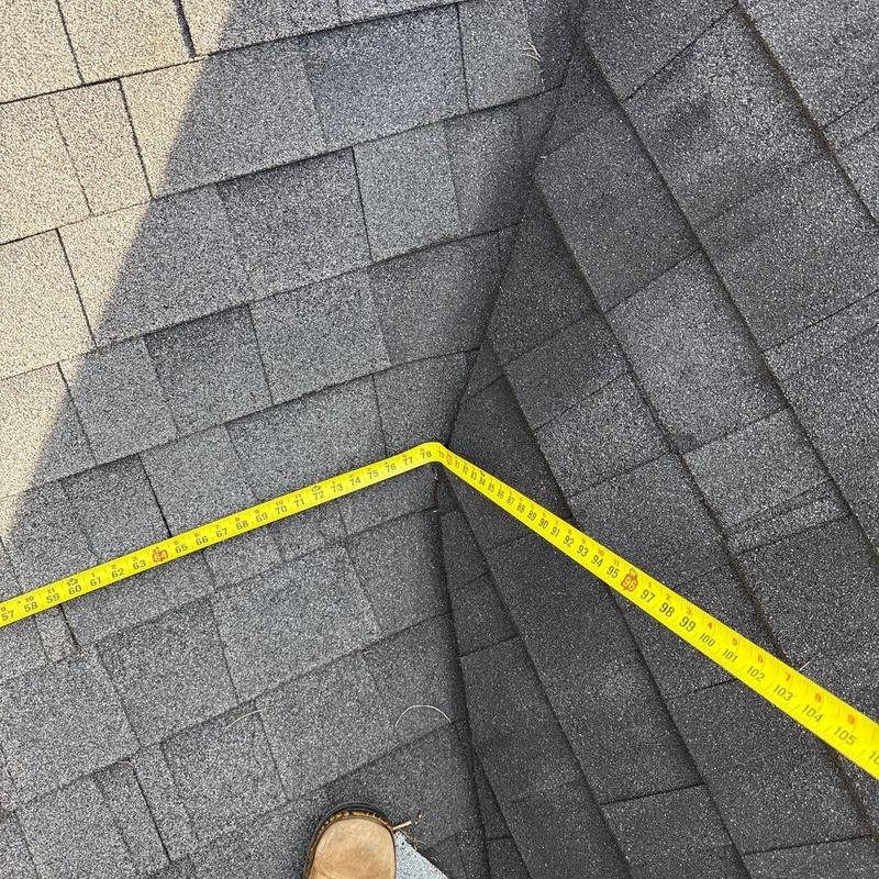 Asphalt shingles with measuring tape on roof valley