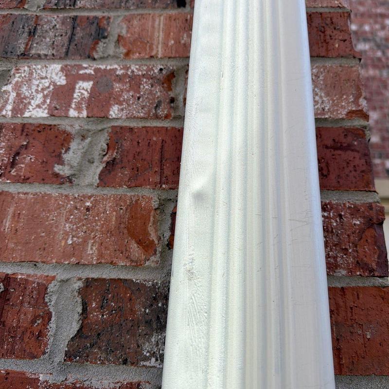 Vinyl siding with visible dent against brick wall