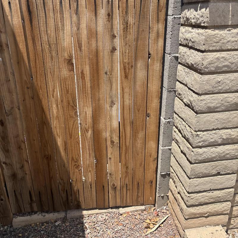 Wooden gate next to stone wall outdoors in sunlight
