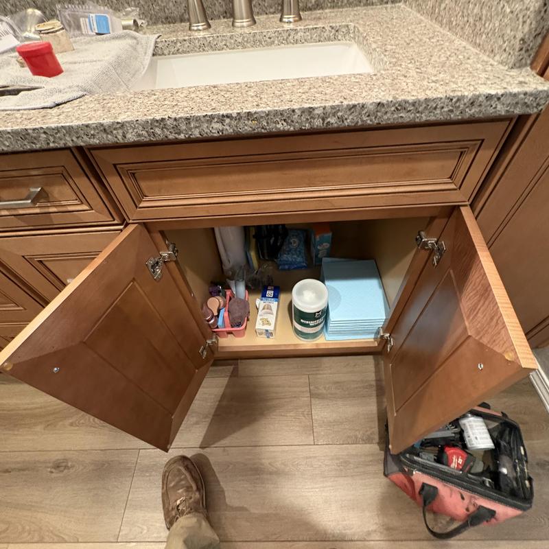 Bathroom vanity cabinet with open doors and supplies
