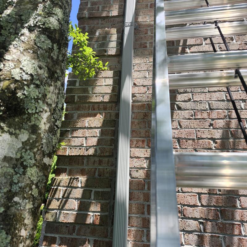 Gutter downspout secured on brick house exterior