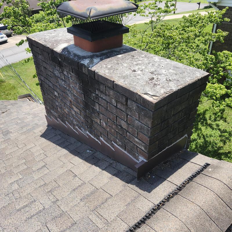 Brick chimney with metal flashing on shingle roof