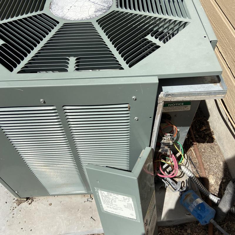 HVAC condenser unit with open electrical panel outdoors