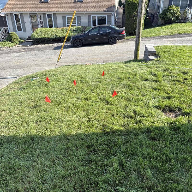 Underground sewer pipe marked with red flags on lawn