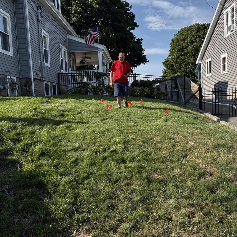 Underground sewer pipe location marked with flags in yard
