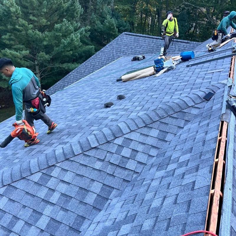 Asphalt shingle roof installation with workers on roof