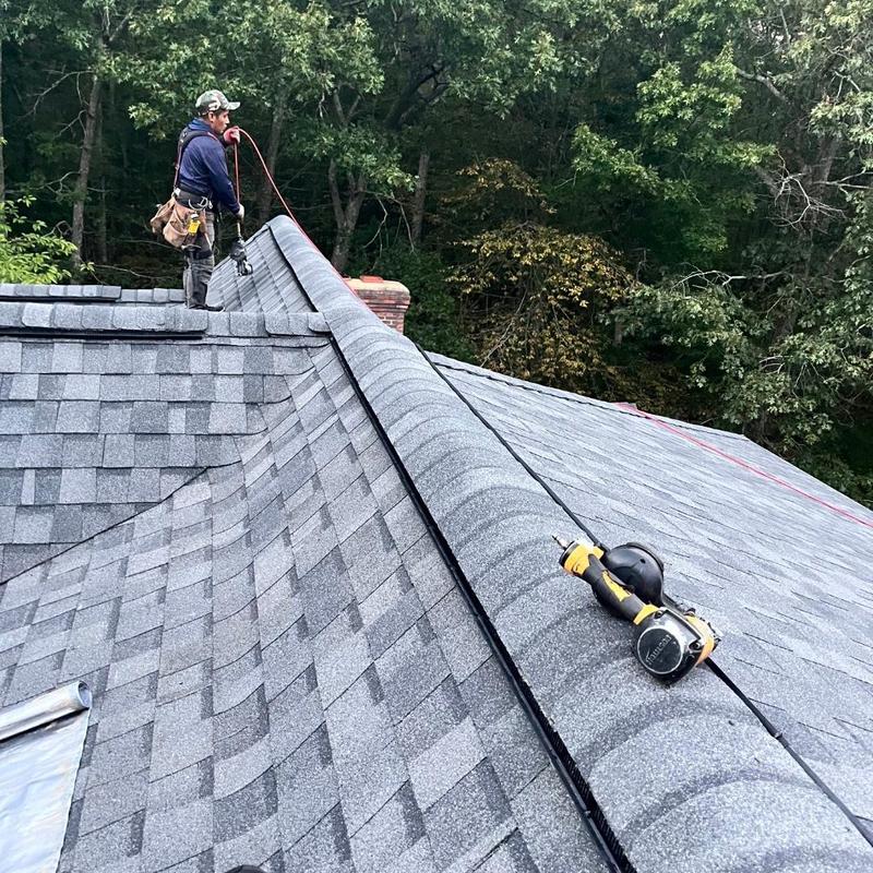 Asphalt shingle roof ridge with nail gun and worker