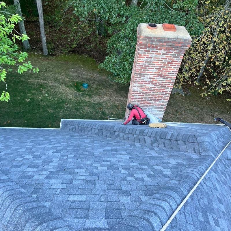Asphalt shingle roof installation near brick chimney