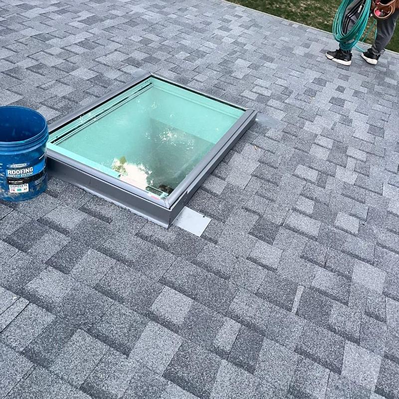 Roof skylight installation on gray shingle roof