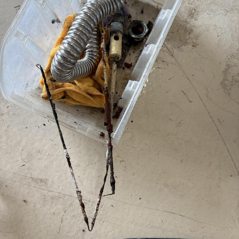 Anode rod and plumbing parts in plastic bin