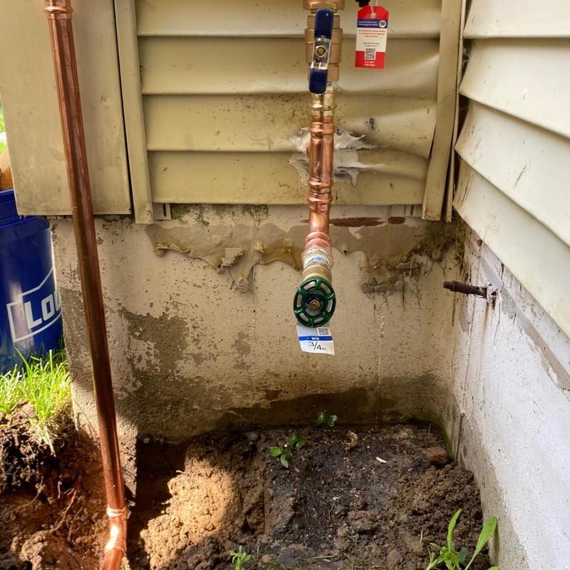 Copper water pipe with valve and fitting near foundation wall