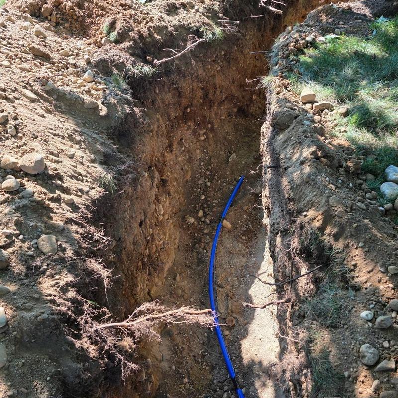Water service line excavation with blue piping installation