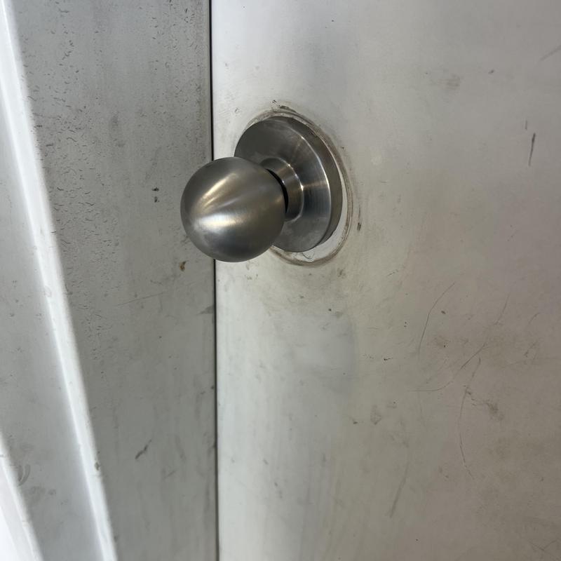 Door knob on worn white door in close-up view