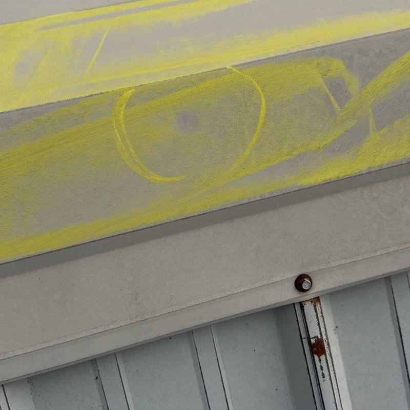 Metal roof panel with hail damage markings and rust spot