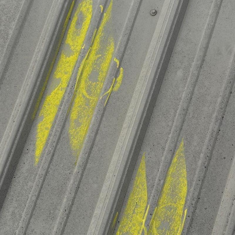 Metal roof panel with hail damage marked in yellow paint