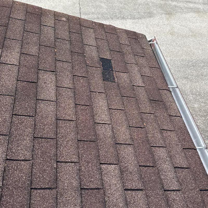 Roof shingles with visible hail damage near gutter edge
