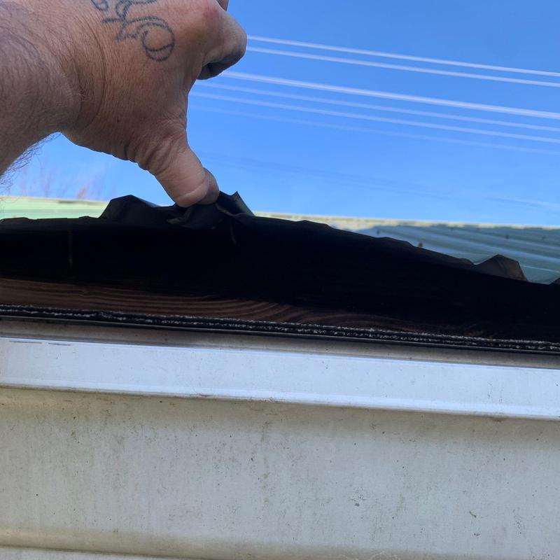 Metal roofing panel lifted showing wood decking underneath