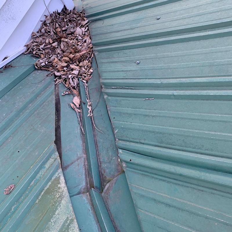 Metal roof valley with leaf debris and slight damage