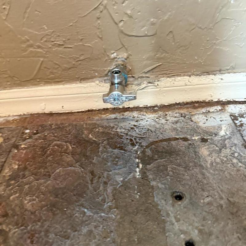 Toilet supply valve on textured floor near wall baseboard Toilet supply valve on textured floor near wall baseboard