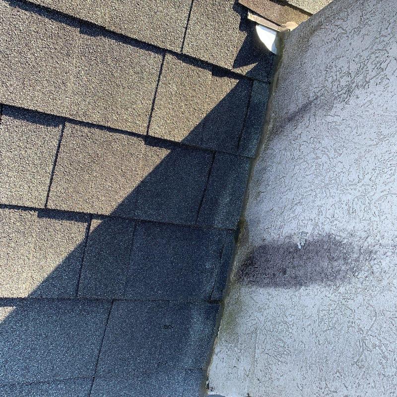 Asphalt roof shingles near wall with hail damage
